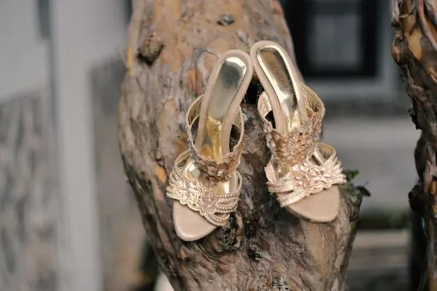 Close-up of a pair of strappy gold sandals with delicate gemstone embellishments, displayed on a velvet cushion. The background is softly blurred to emphasize the intricate details of the sandals and their luxurious appeal.