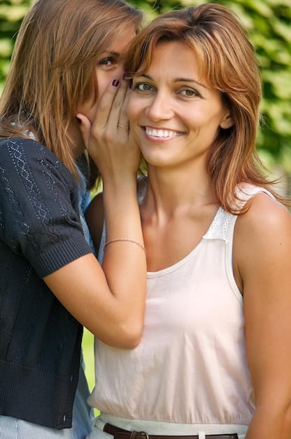 A candid photo of Jennifer Aniston and Courteney Cox hugging warmly, capturing a light-hearted moment. Both are dressed casually, emphasizing their close off-screen friendship and strong bond from the 