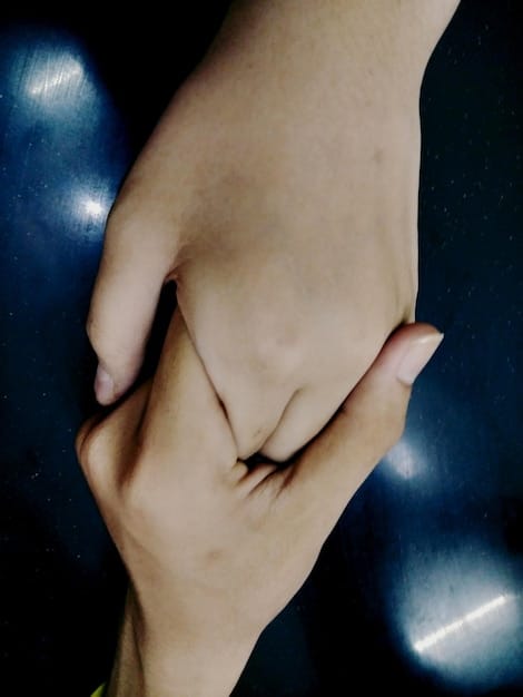 A close-up shot of two hands intertwined, symbolizing trust and connection in a relationship. The background is blurred to keep the focus on the hands.