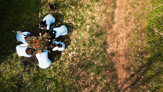 A drone shot of a tree planting event organized by an award show. Volunteers are planting trees, and the award show's logo is visible on banners.