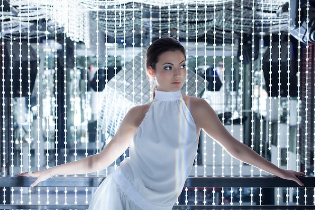 A long shot of a celebrity wearing a 3D-printed dress with integrated LED lights that pulse and change color in response to their movements. The dress appears both futuristic and elegant, highlighting innovation.
