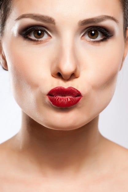 A close-up of red lips with perfect makeup. There is a matte finish and the lips are plump and full.
