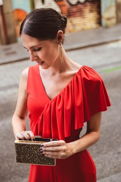 A celebrity holding a stylish clutch on the red carpet, highlighting the handbag's role as the perfect companion to her gown.