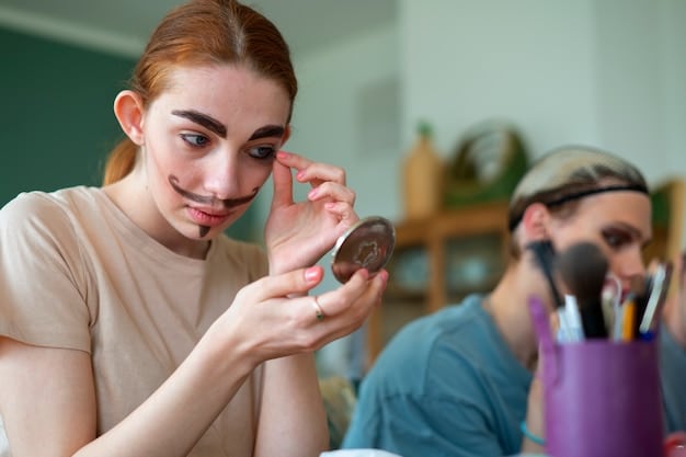 A celebrity makeup artist applying foundation to a client's face using a makeup sponge. The lighting is bright and the artist is focused on achieving an even and seamless application.