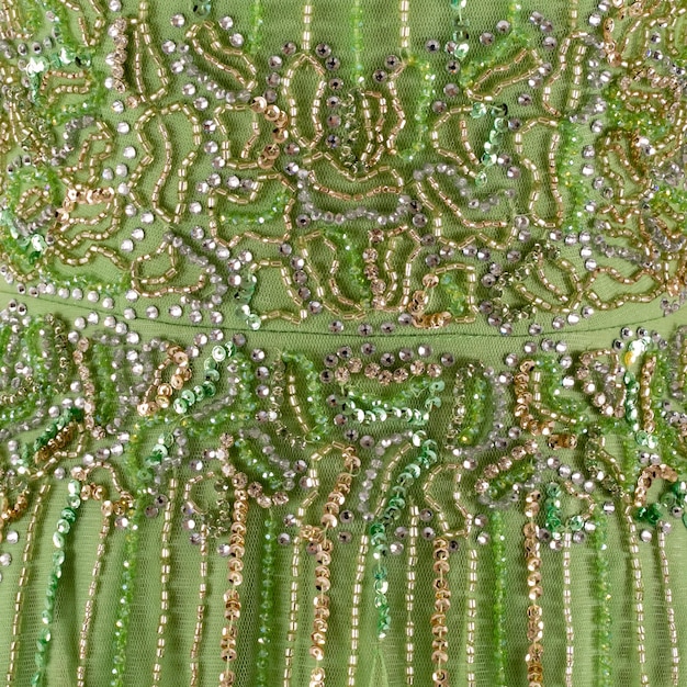 A close-up shot of a gown's bodice, highlighting intricate embroidery and beadwork depicting natural motifs like flowers and leaves, symbolizing the personal touch and craftsmanship in red carpet fashion.